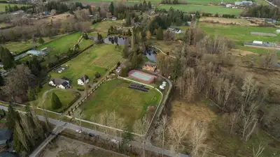 A peaceful 4.64-acre ALR property in South Surrey with a pond, mature trees and white PVC-fenced fie...