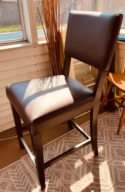 2 counter height stools. Dark brown stained wooden legs. Brown leather upholstery. Made by Canadian...