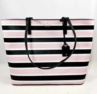 This Kate Spade tote is perfect for everyday use, featuring a stylish striped design in pink, black,...