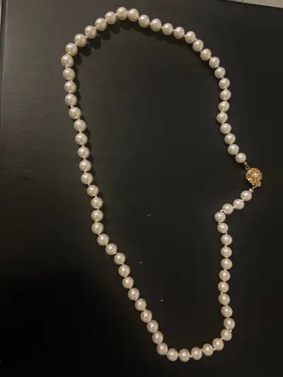 This is a classic pearl necklace with a decorative gold clasp, perfect for adding a touch of eleganc...