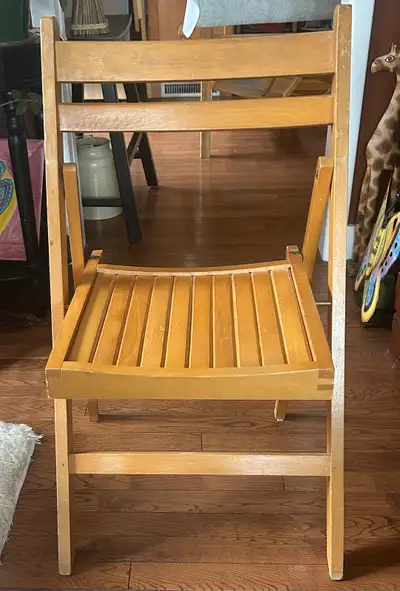 A simple wooden folding chair in excellent condition. It's made of light-coloured wood and has a sla...