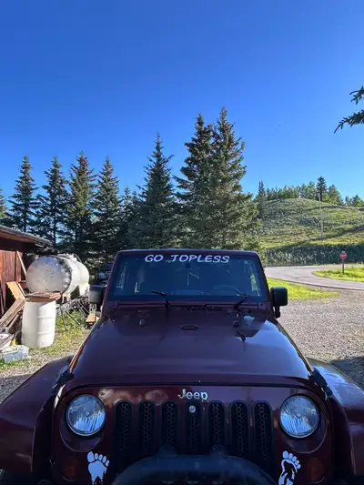 This pre-owned 2009 Jeep Wrangler Sahara comes equipped with rugged aftermarket wheels and distinct...