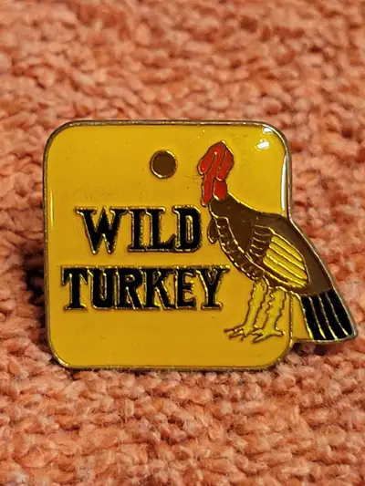 Cool Wild Turkey enamel pin. Has a turkey graphic on yellow background. Measures about 1 inch wide....