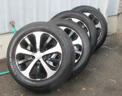 Four 235/60 R18 Michelin Defender LTX M/S tires, half worn on original rims