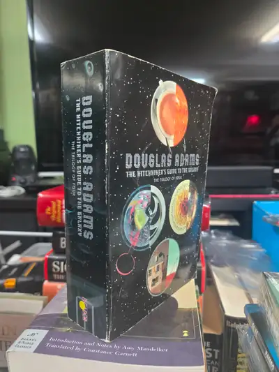 This used copy of Douglas Adams' The Hitchhiker's Guide to the Galaxy: The Trilogy of Four is a clas...