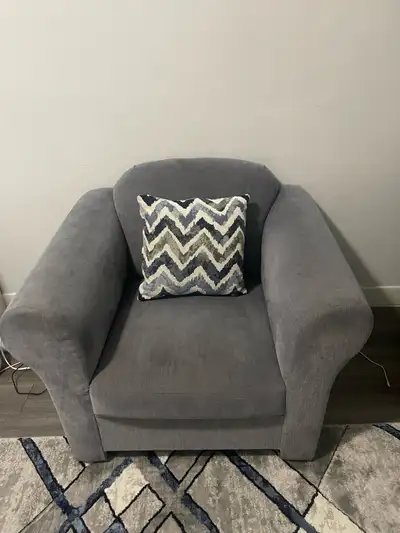 This comfy grey armchair is perfect for any living space! It's in used condition, showing some signs...