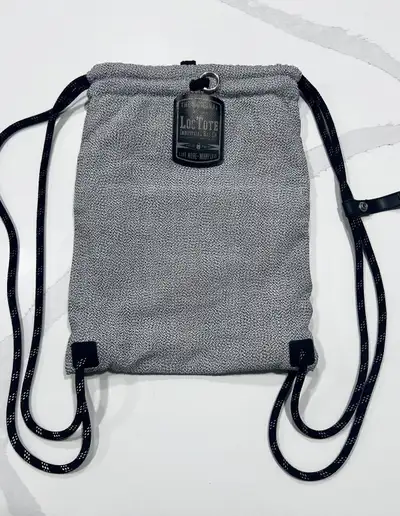 This is a Loctote Flak Sack SPORT, an anti-theft drawstring backpack designed with slash-resistant f...