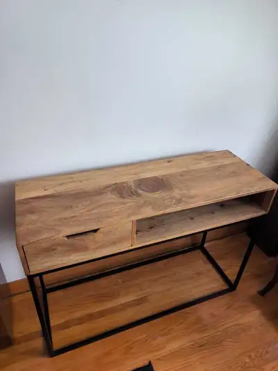 This console table features a stylish wood top with a sleek black metal frame, and includes a drawer...