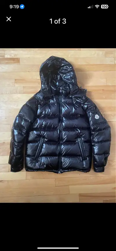 Get ready to turn heads with this sleek, black Moncler puffer jacket, a stylish addition to any ward...