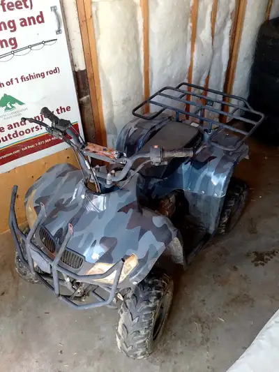 This grey camouflage ATV is a fun-sized ride for young adventurers, featuring a cargo rack for hauli...