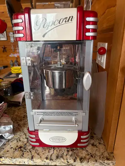 Make movie nights magical with this Nostalgia red and silver popcorn machine! This unit features a s...