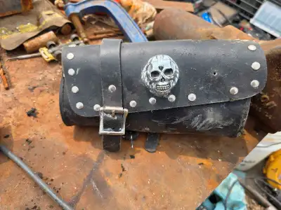 This black leather motorcycle tool bag features a skull design and studded accents, perfect for addi...