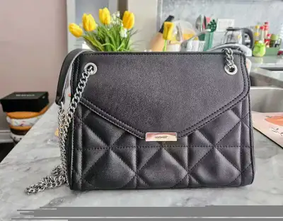 This is a stylish, pre-owned black nine west handbag featuring a quilted design and silver chain str...