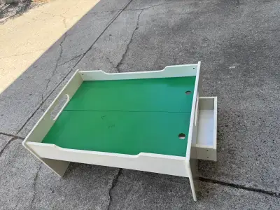 This pre-loved wooden train table features a spacious green play surface and two convenient built-in...