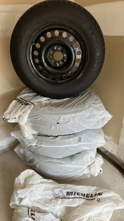 Offering a set of four Michelin X-Ice Snow winter tires, size 235/65R17, mounted on black steel rims...