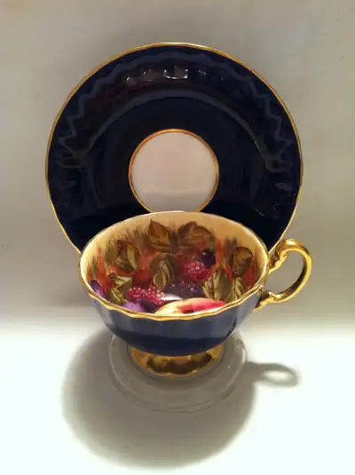 A rare, cobalt blue English Bone China teacup and saucer from John Aynsley decorated with an orchard...