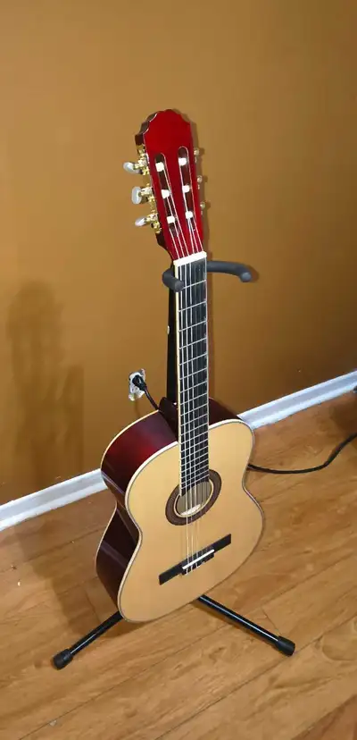 Beautiful classical guitar with a natural wood finish top and reddish-brown back and sides. This 6-s...