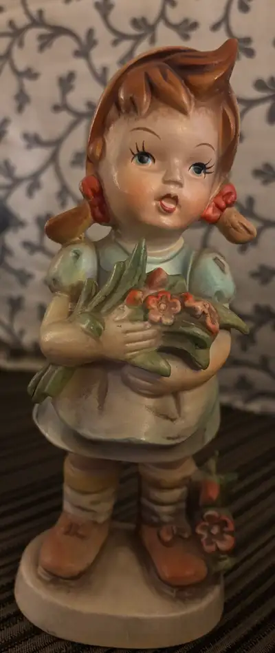 This is a vintage Goebel figurine of a girl holding flowers, showcasing the classic Hummel style. It...